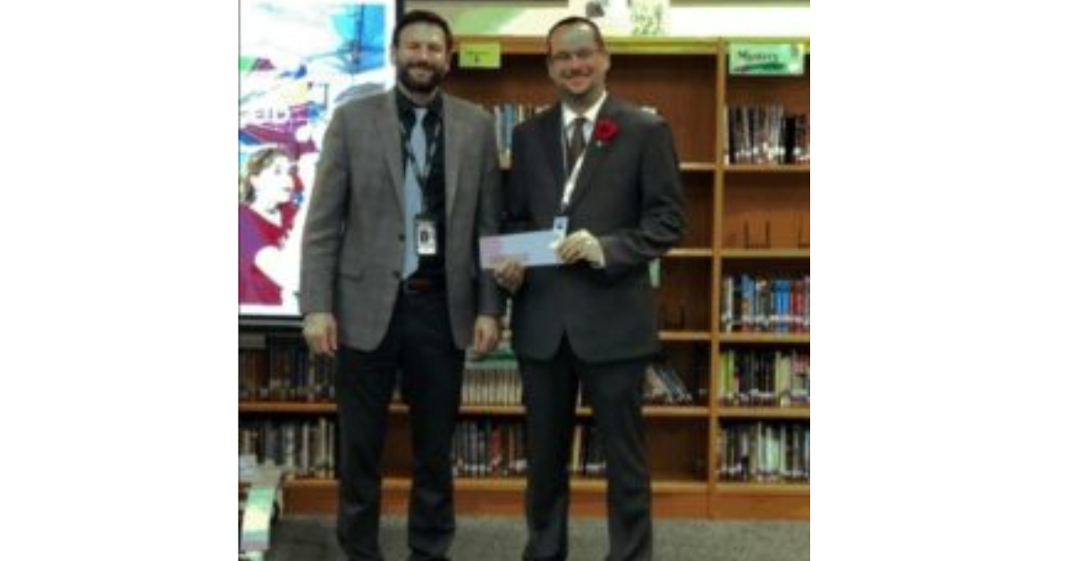 Avon Central School District High School Principal Ryan Wagner presents Livingston County Veteran Services Director David Terry (right) with a donation for the department.